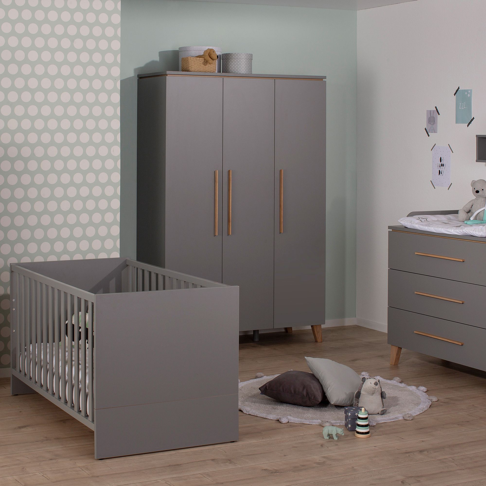 Modernes graues Kinderzimmer mit Kinderbett, Kleiderschrank, Kommode und Plüschtieren auf einem Teppich.