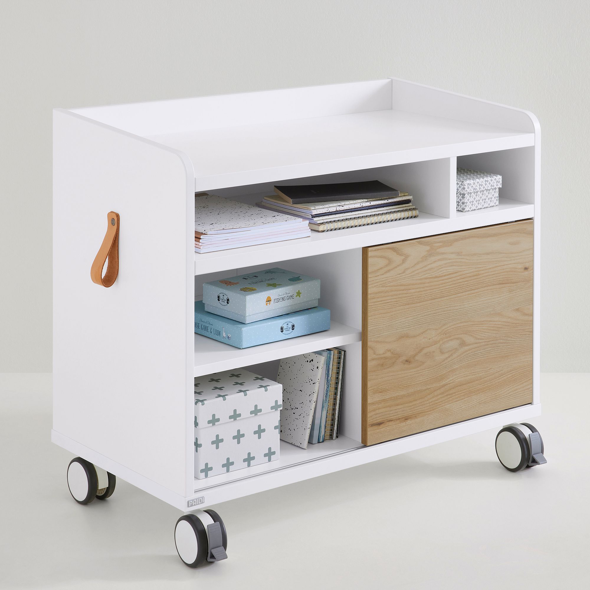 Weißer rollender Aufbewahrungswagen mit Regalen, Büchern, Kisten und einer holzgetäfelten Tür.