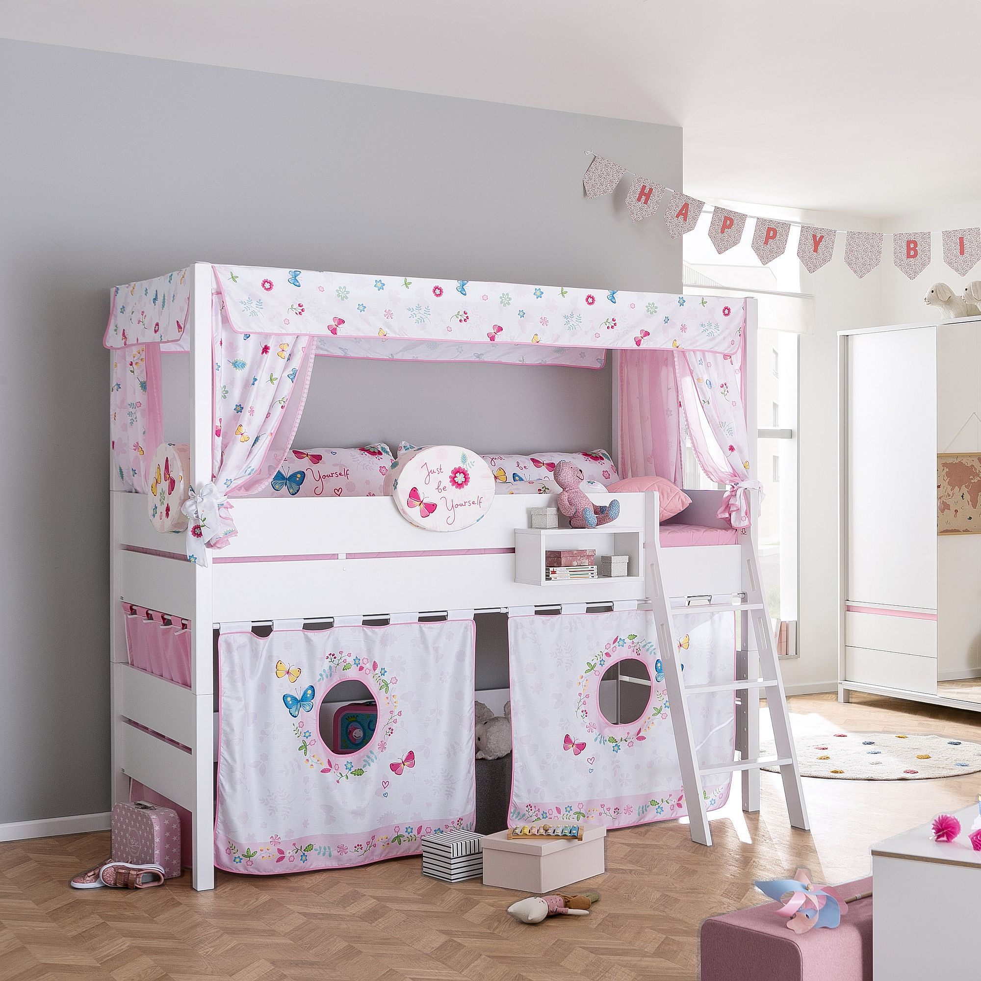 Rosa-weißes Kinderetagenbett mit Schmetterlingsdekor und Spielzeug in einem hellen Schlafzimmer.