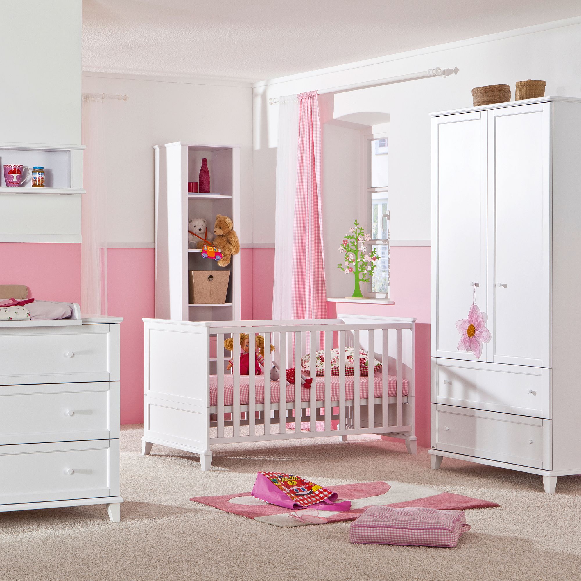 White and pink baby nursery with crib, wardrobe, dresser, and stuffed animals.