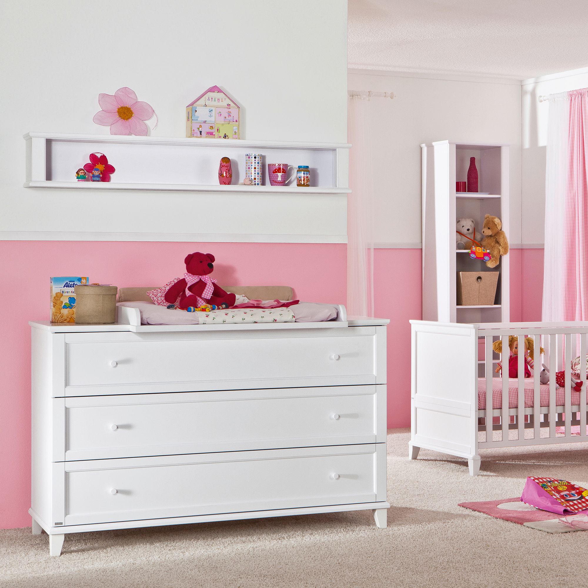 Pink and white nursery with crib, dresser, and shelves holding toys and decorations.