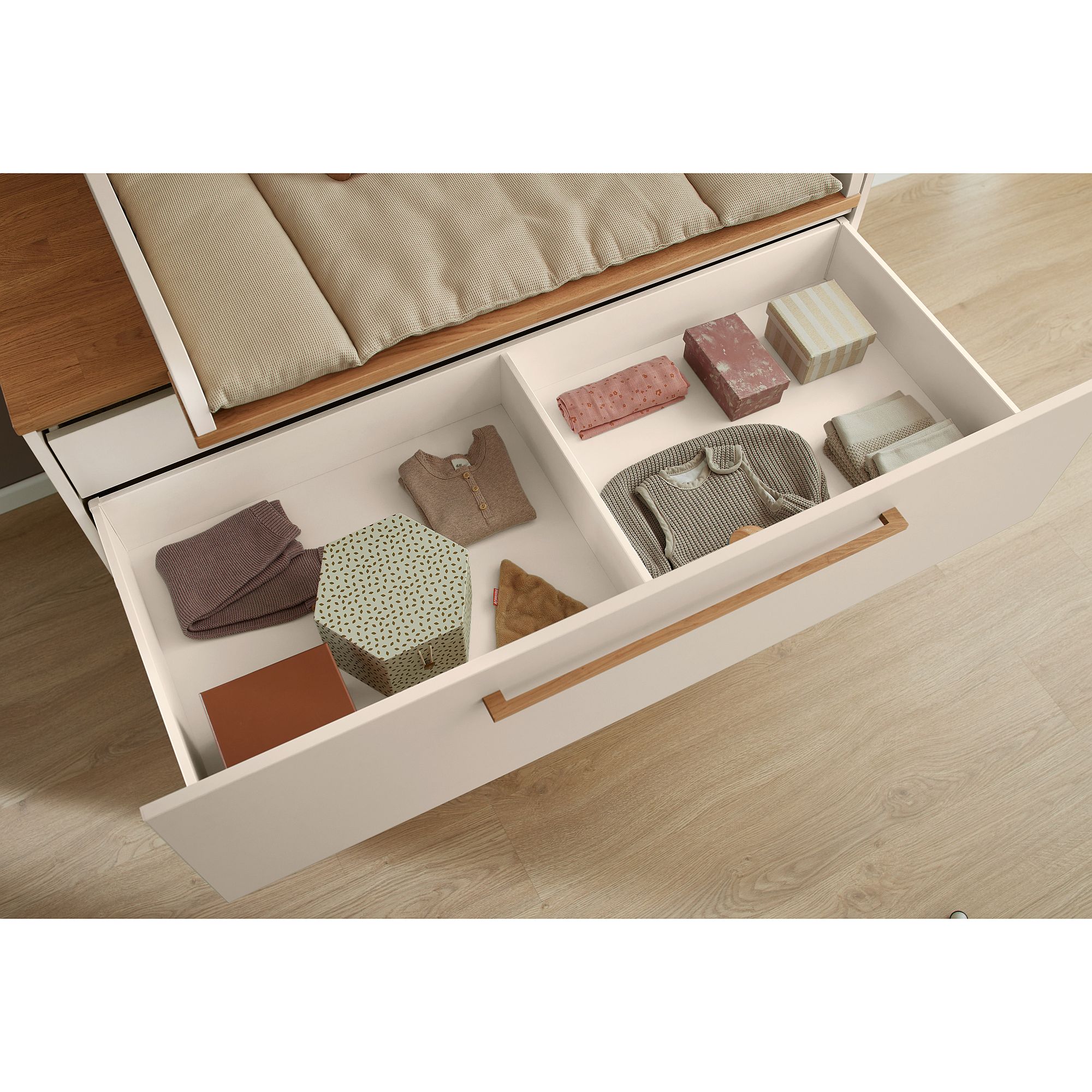 Offene Schublade mit ordentlich gefalteter Kleidung und mehreren gemusterten Schachteln darin.