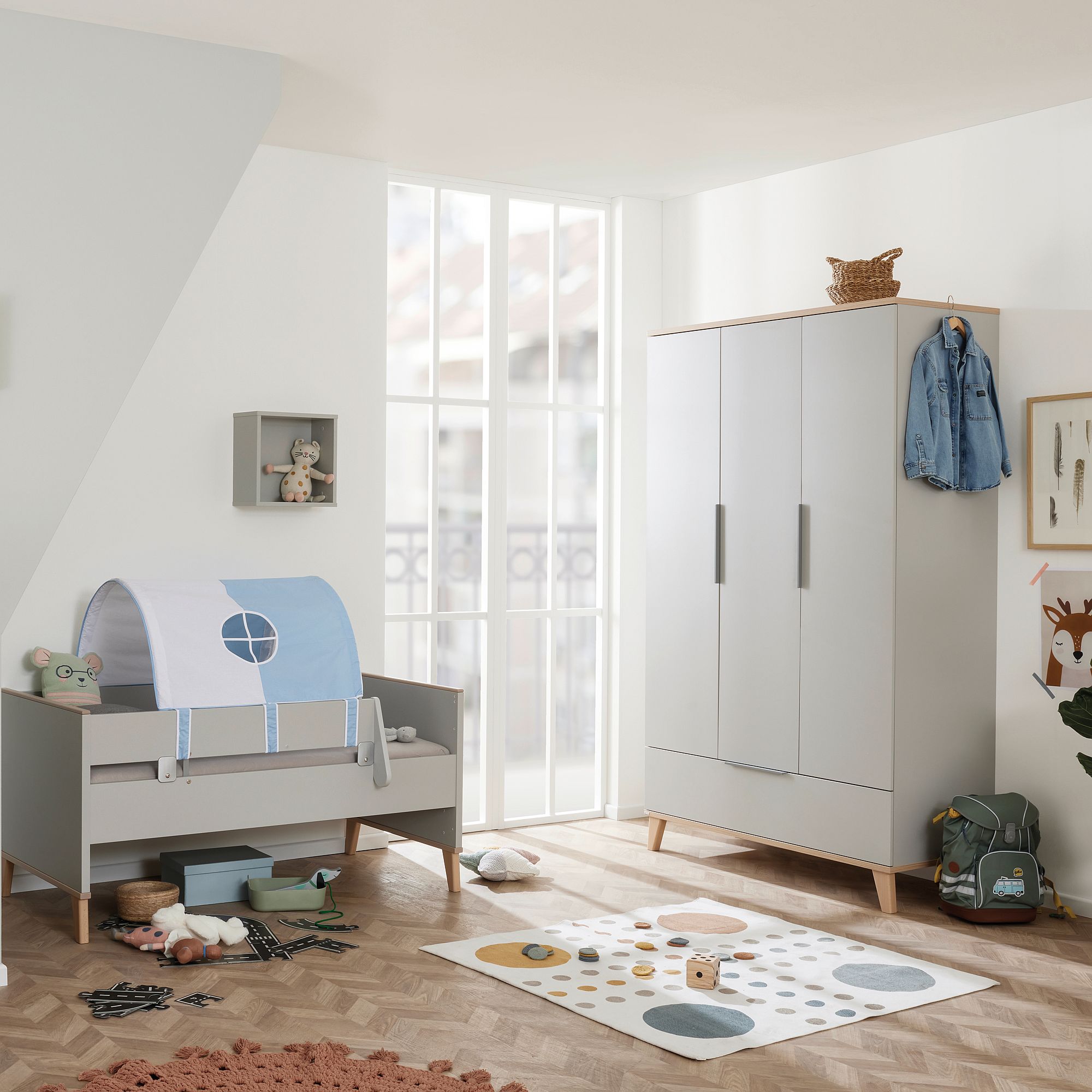 Modernes Kinderzimmer mit Kinderbett, Kleiderschrank, Spielzeug und sanfter, natürlicher Beleuchtung.