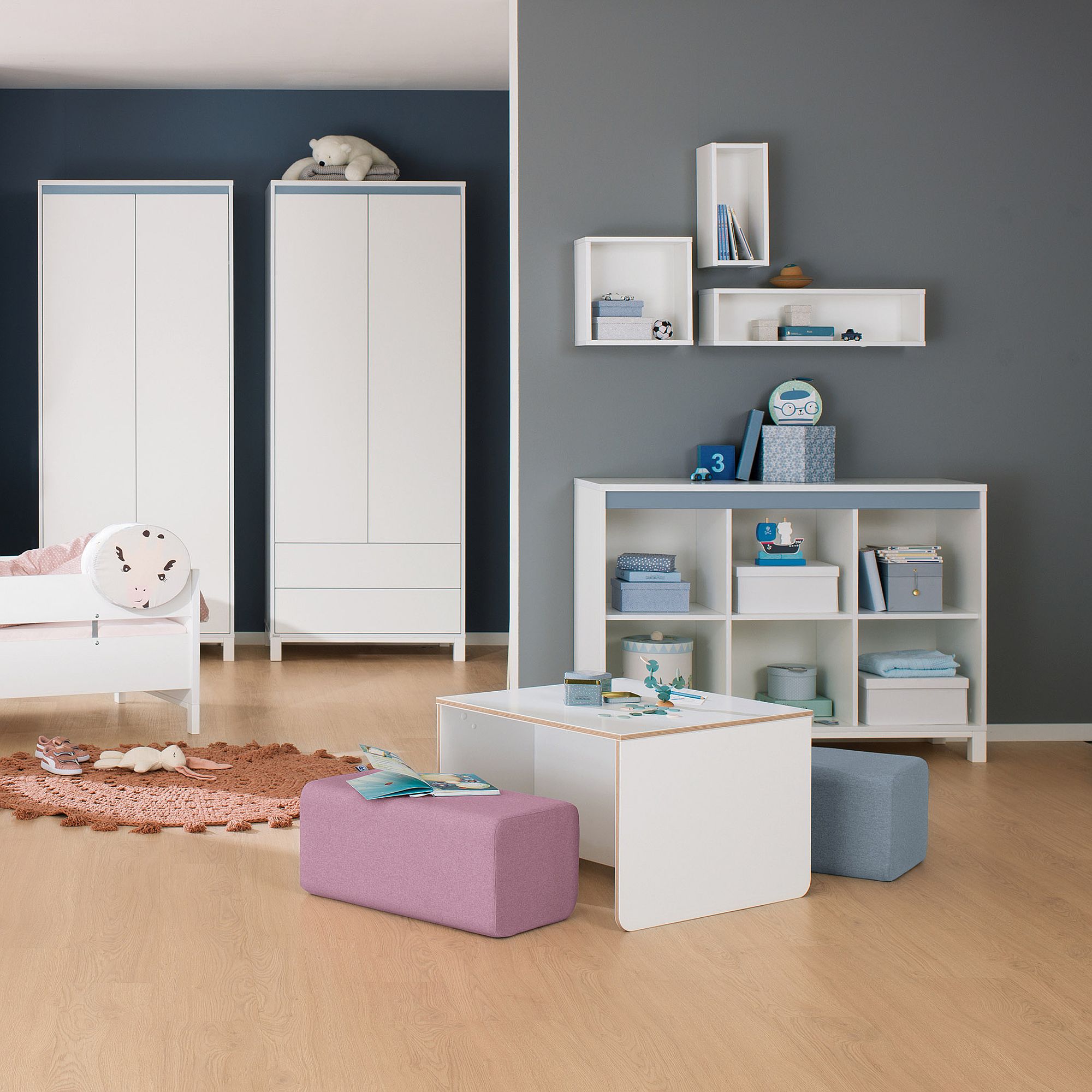 Modernes Kinderzimmer mit weißen Möbeln, Regalen und pastellfarbenen Sitzgelegenheiten.