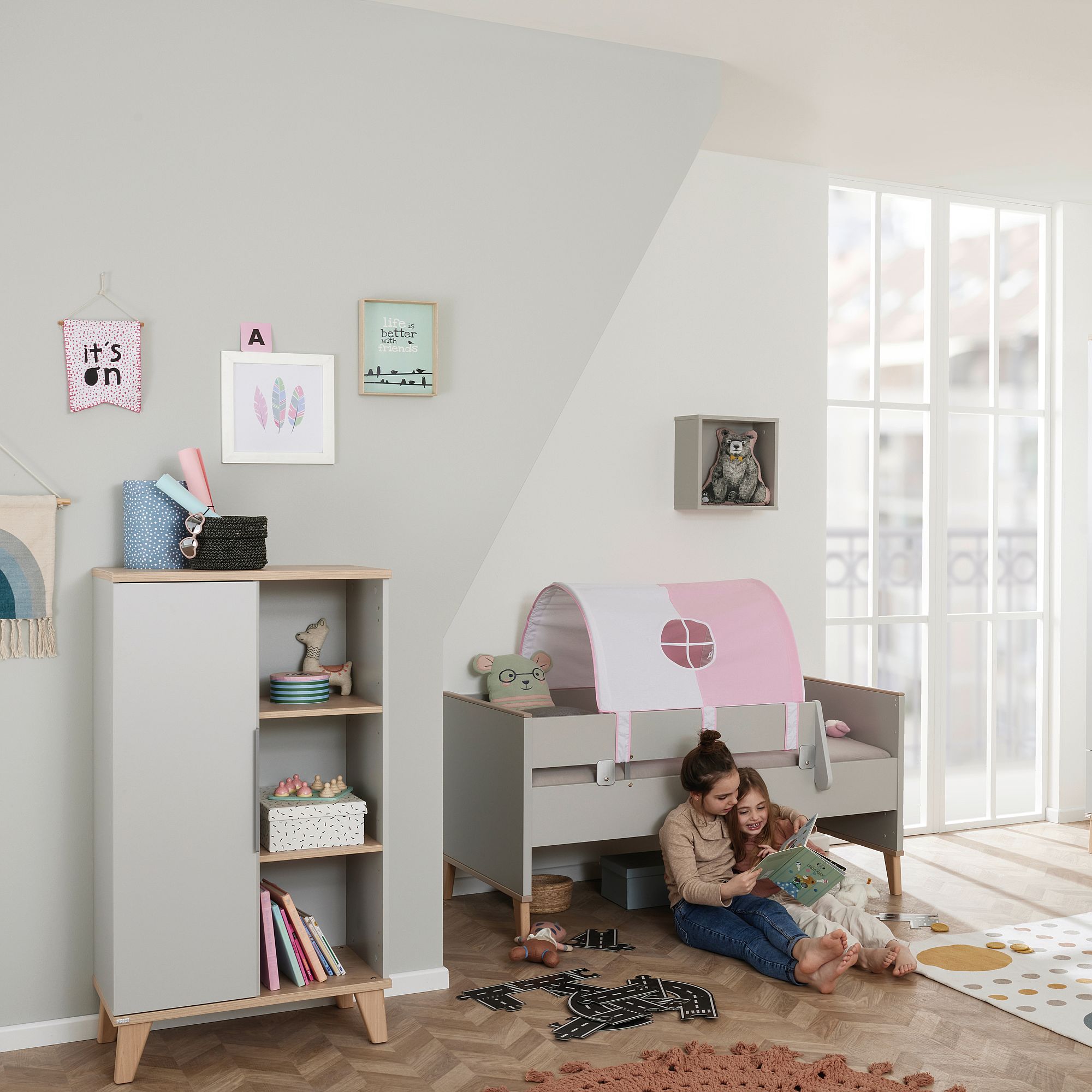 Standregal Fiene mit 1 Türe links und 3 offenen Fächern Zwei Kinder lesen unter einem kleinen Bett in einem hellen, modernen Kinderzimmer.