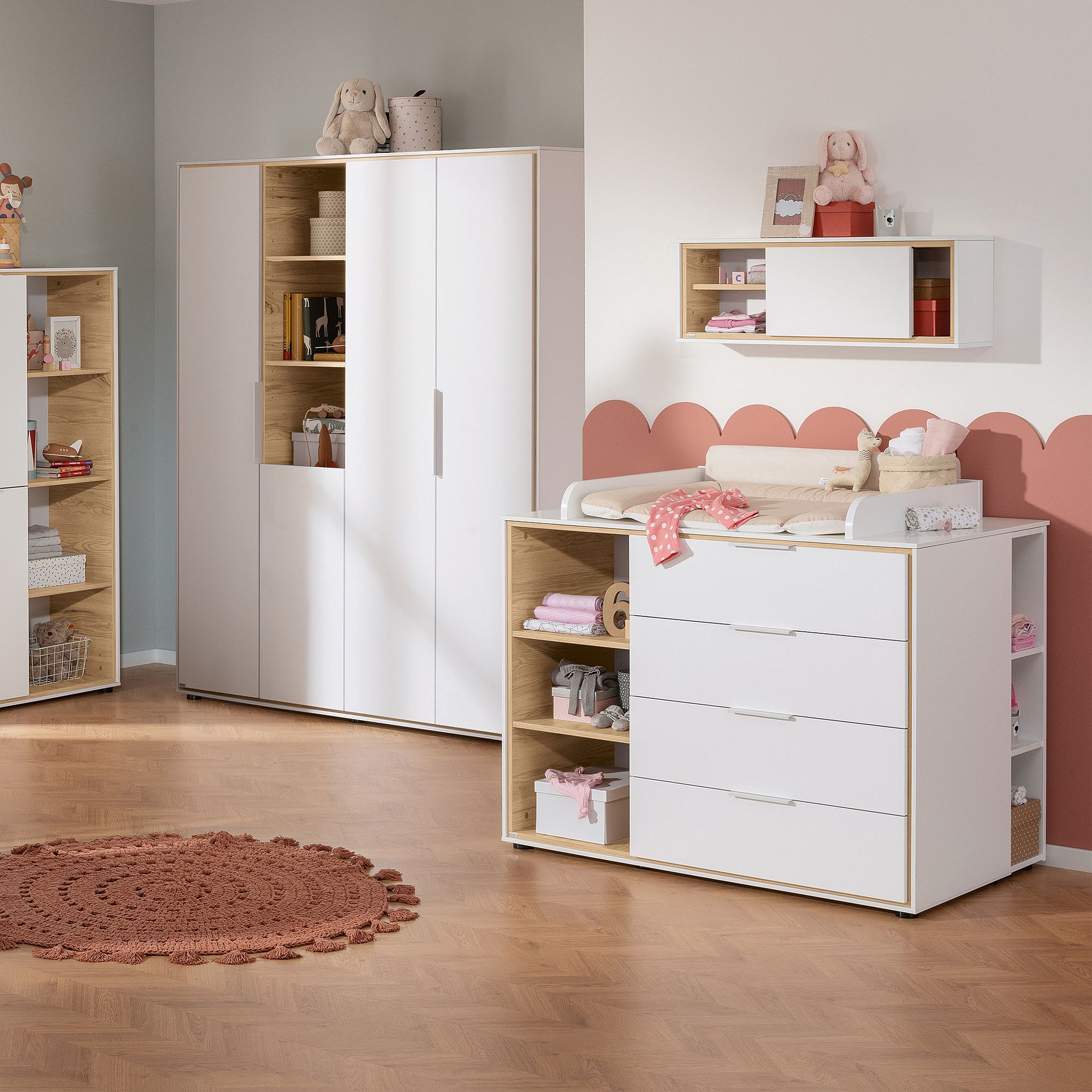 Modernes Kinderzimmer mit weißen Möbeln, Wickeltisch und Spielzeug auf Holzboden.