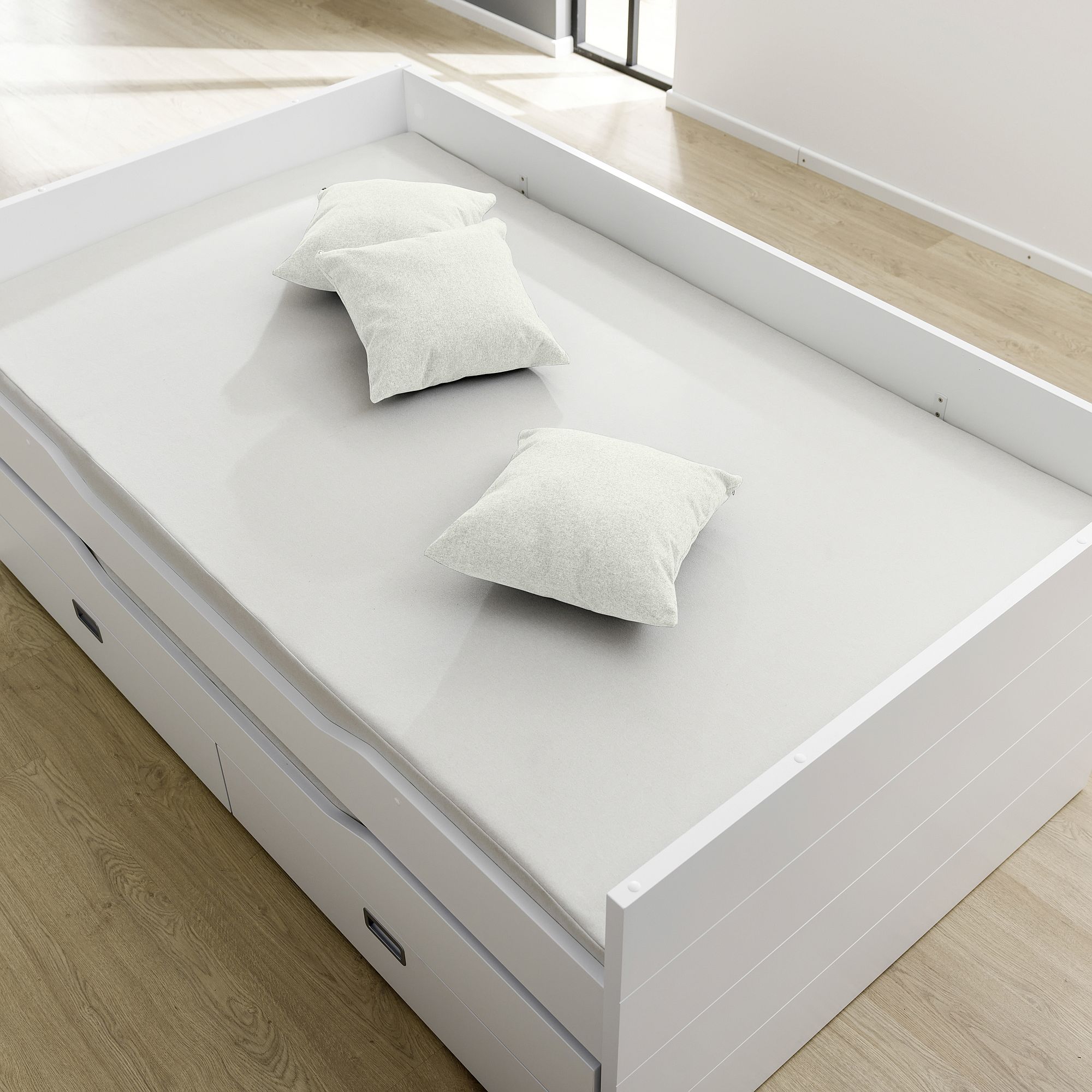 Partykissen  40 x 40 cm im Mikrofaserbezug Ivory Ein weißes Bett mit drei weißen Kissen, auf einem hellen Holzboden.