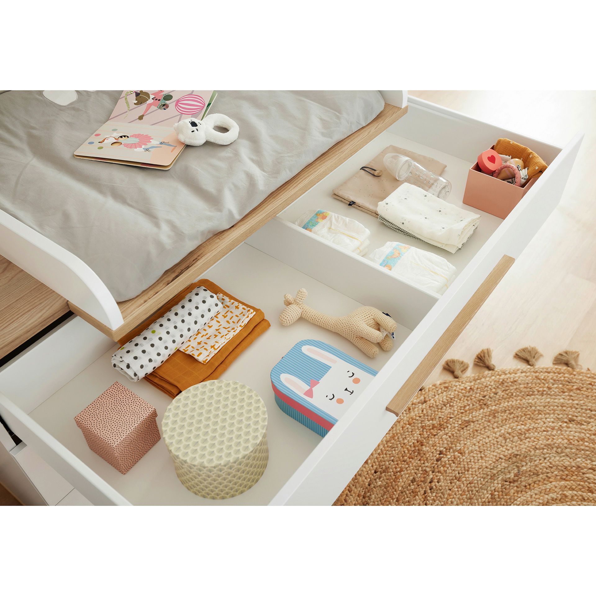 Open drawer with neatly organized baby items, toys, and folded clothes inside.