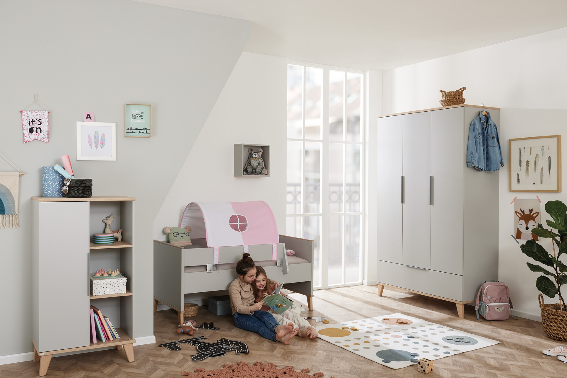 Two children read together in a bright, modern, and tidy kids bedroom.