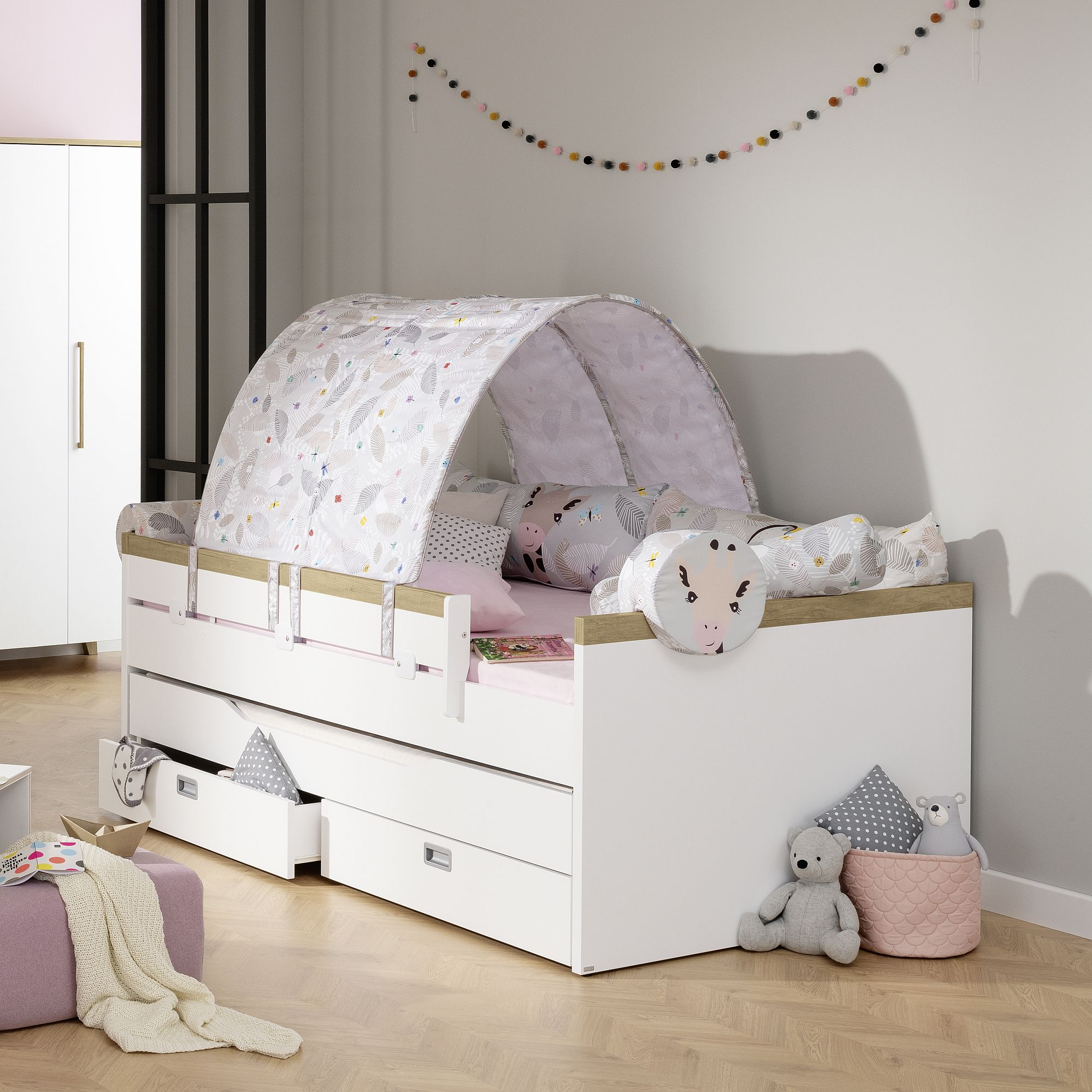 Children’s bed with a canopy, plush toys, and storage drawers underneath.