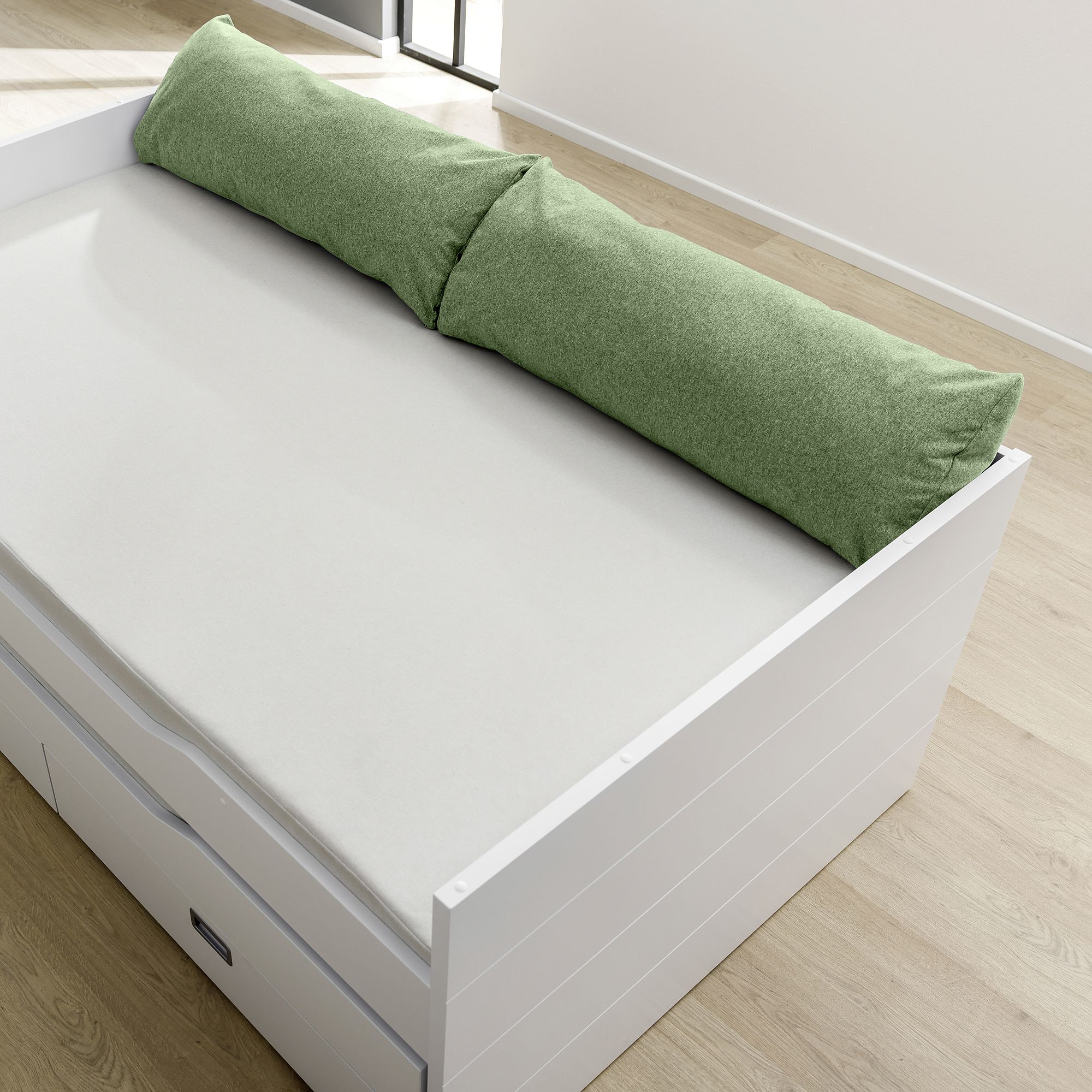 White daybed with storage drawers and two green bolster pillows on top.