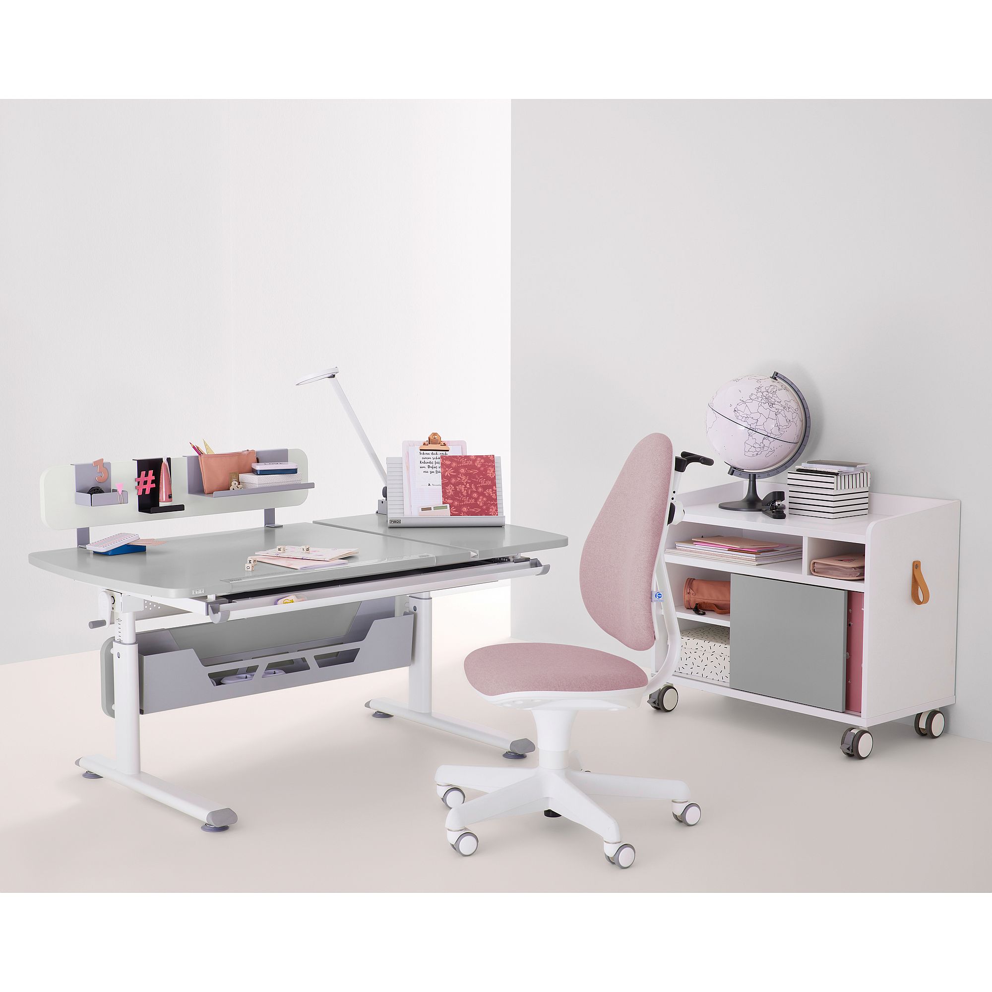 Rollcontainer Rollcaddy mit 1 Schiebetür in Kieselgrau Minimalistischer Schreibtisch mit rosa Stuhl, Lampe, Stauraum und einem Globus.