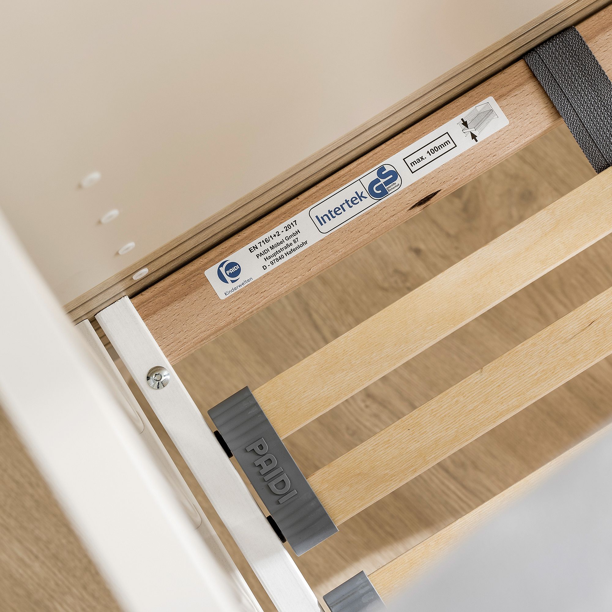 Nahaufnahme eines Lattenrosts mit Zertifizierungsetiketten und verstellbaren Schlitzen.