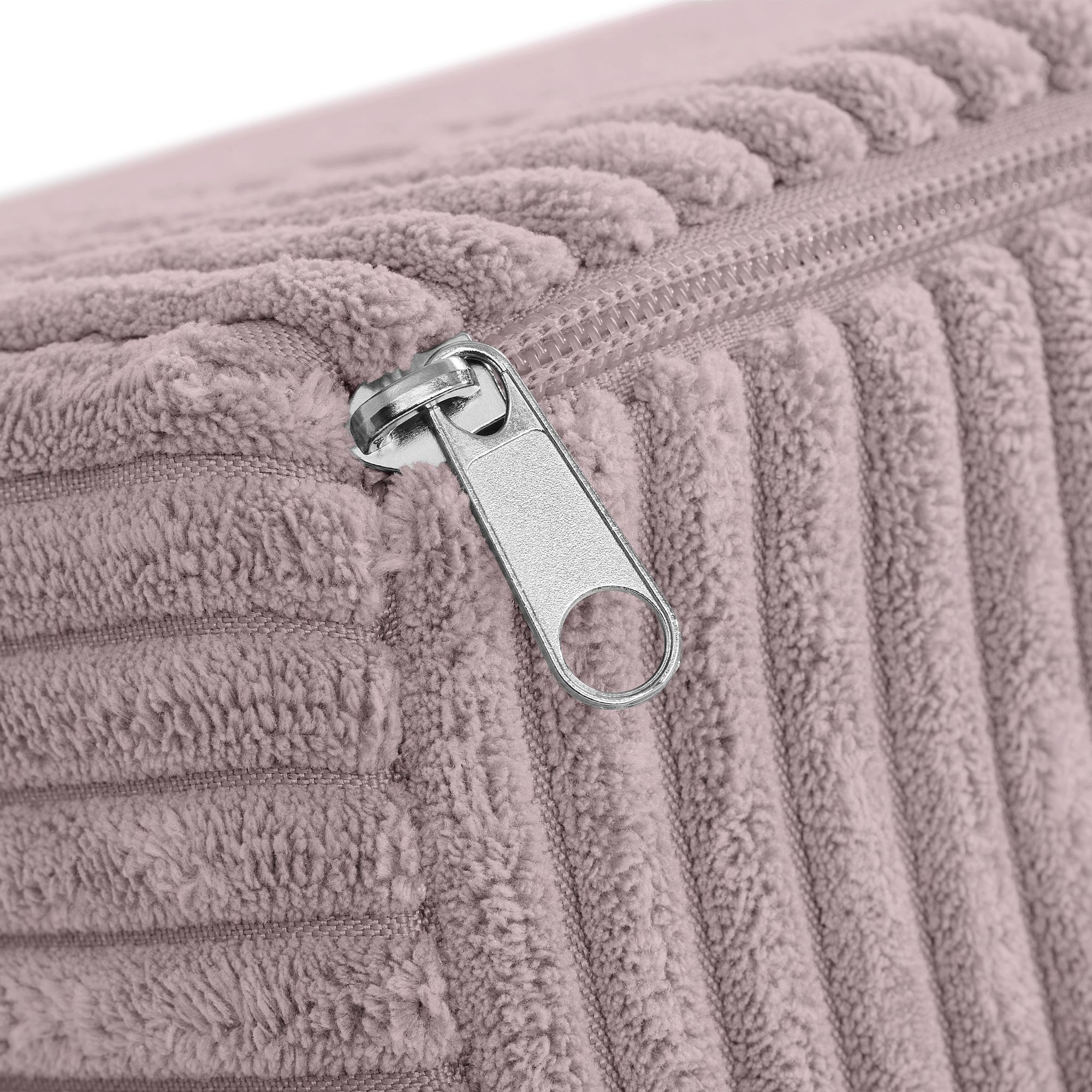 Nahaufnahme eines silbernen Reißverschlusses auf einem strukturierten, gerippten, lila Stoffkissenbezug.